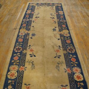 Gold and navy floral runner rug with scattered motifs displayed on aged wooden plank flooring.