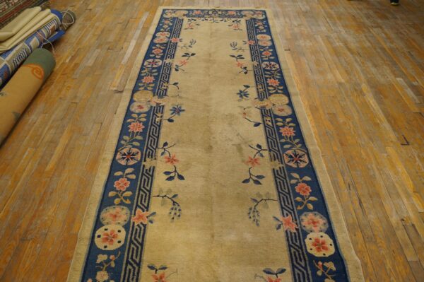 Gold and navy floral runner rug with scattered motifs displayed on aged wooden plank flooring.