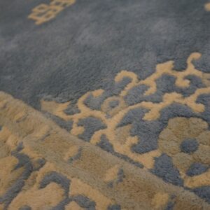 High-pile dusty blue rug with carved beige scrolling floral and traditional medallion patterns visible up close.