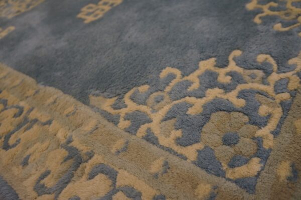 High-pile dusty blue rug with carved beige scrolling floral and traditional medallion patterns visible up close.