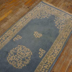 Plush blue runner rug with carved beige scroll and fret patterns on rustic wood floor.