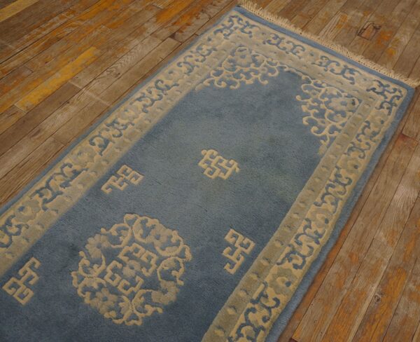 Plush blue runner rug with carved beige scroll and fret patterns on rustic wood floor.