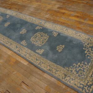 Blue runner rug with beige border and traditional motifs rests on aged hardwood planks.