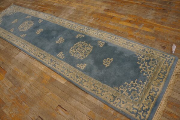 Blue runner rug with beige border and traditional motifs rests on aged hardwood planks.