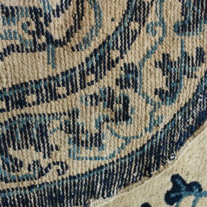 Detail of a tan and blue woven geometric patterned rug meeting a contrasting shaggier cream rug section.