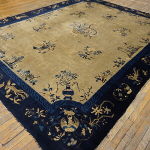 Muted gold and navy rug featuring traditional floral and animal motifs displayed on distressed wood floors.
