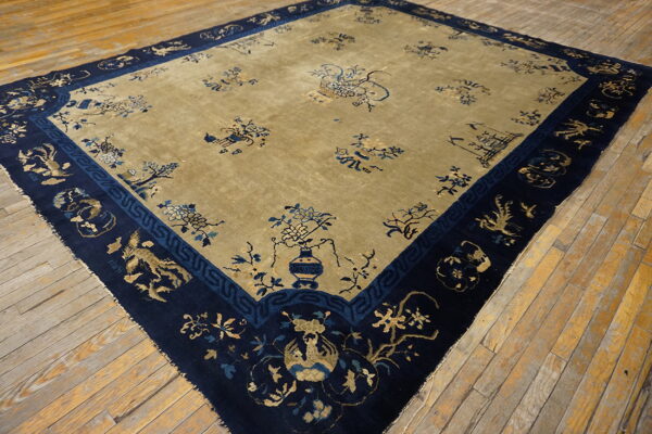 Muted gold and navy rug featuring traditional floral and animal motifs displayed on distressed wood floors.