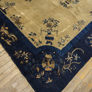 Navy and khaki traditional rug corner showing floral and vase motifs on distressed wood flooring.
