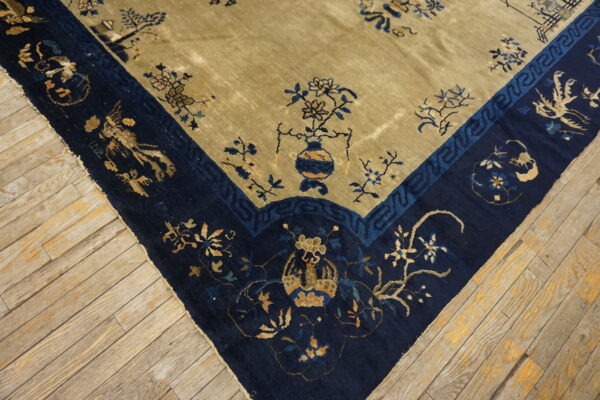 Navy and khaki traditional rug corner showing floral and vase motifs on distressed wood flooring.