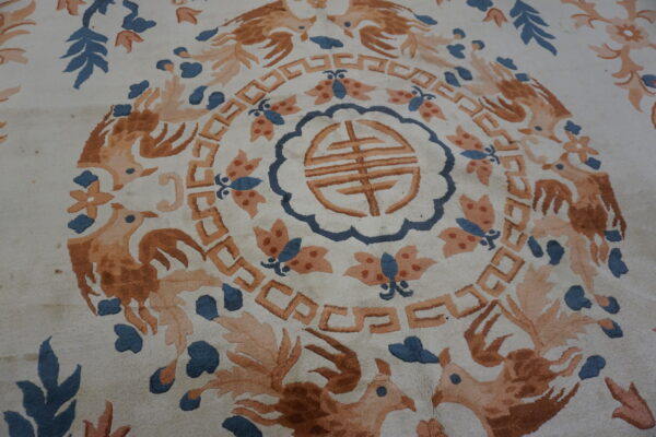 Ornate cream rug featuring a central medallion, rust-orange birds, blue leaves, and geometric motifs.