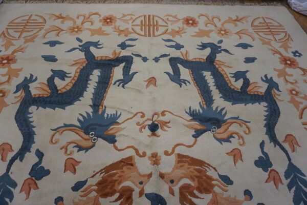 Cream rug with mirrored blue dragons, orange floral motifs, and symbolic designs.