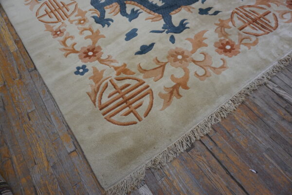 Light beige rug featuring a blue dragon, orange flowers, and shou symbols on rustic wooden floors.