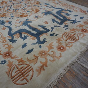 Beige rug with blue dragon and orange floral pattern rests on distressed gray wood floors.