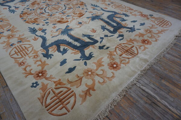 Beige rug with blue dragon and orange floral pattern rests on distressed gray wood floors.