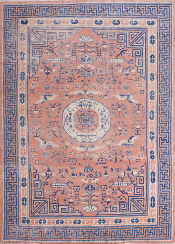 Pink rug with low pile features a detailed blue and cream stylized floral and geometric design.