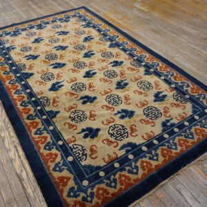 A traditional blue, cream, and rust patterned rug lies on a rustic, distressed wooden plank floor.