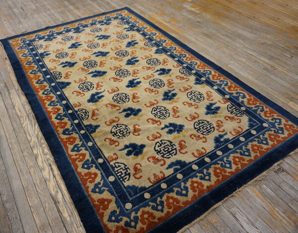 A traditional blue, cream, and rust patterned rug lies on a rustic, distressed wooden plank floor.