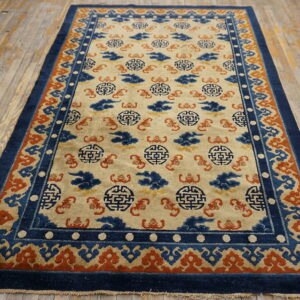 Low-pile rug featuring a cream field, blue medallions, and an orange patterned border on worn wood floors.