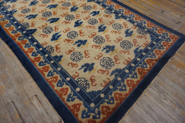 Cream rug featuring blue and terracotta geometric and cloud motifs rests on rustic wood floors.