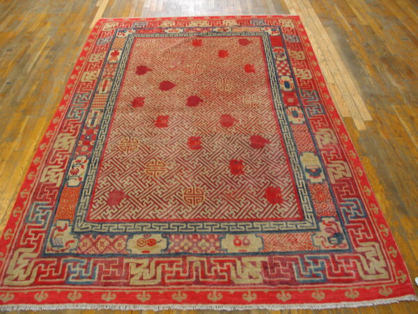 Red, beige, and blue traditional rug featuring intricate geometric lattice patterns on light wood flooring.