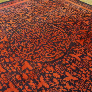 Red and navy rug with an intricate floral pattern and central medallion lying on wood floor.
