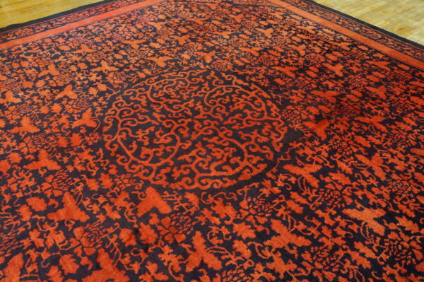 Red and navy rug with an intricate floral pattern and central medallion lying on wood floor.