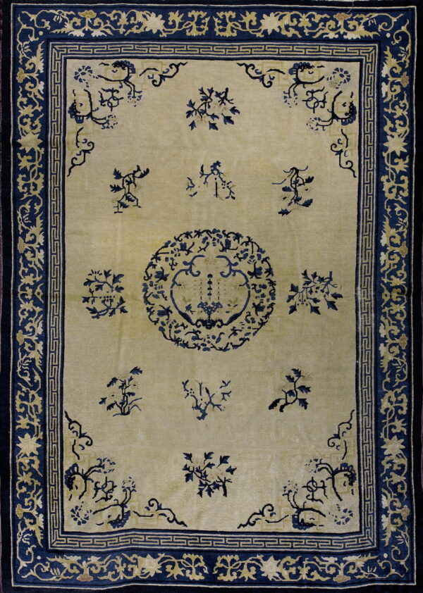 A traditional rug with a tan field and navy blue borders featuring floral and geometric motifs.