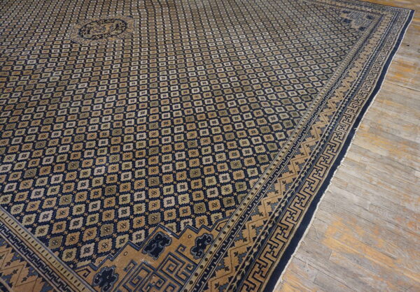 Geometric navy blue and tan rug with a central medallion rests on worn wood planks.