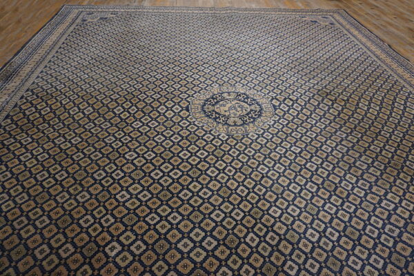 Oversize blue rug with repeating diamond pattern and circular tan medallion on hardwood flooring.
