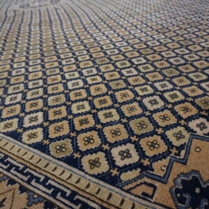 Low-pile rug in navy and tan with a dense, repeating geometric floral pattern and visible borders.
