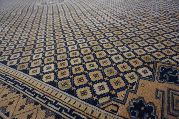 Low-pile rug in navy and tan with a dense, repeating geometric floral pattern and visible borders.