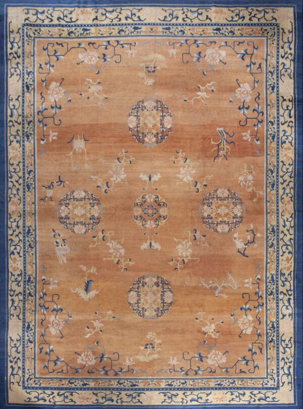 Orange rug featuring light blue and cream floral medallions, framed by a wide navy and cream border.