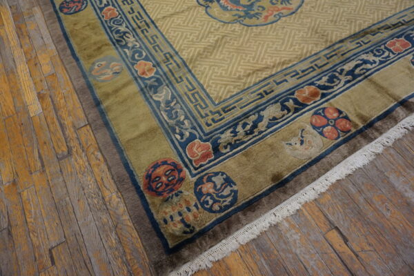 Geometric khaki rug with wide olive and cobalt blue borders featuring floral medallions on distressed wood floors.