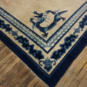 Cream rug corner with a navy blue dragon and wave border rests on distressed wooden floorboards.