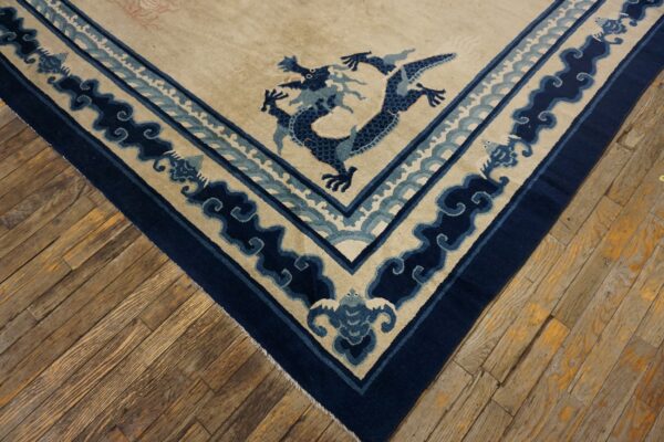Cream rug corner with a navy blue dragon and wave border rests on distressed wooden floorboards.