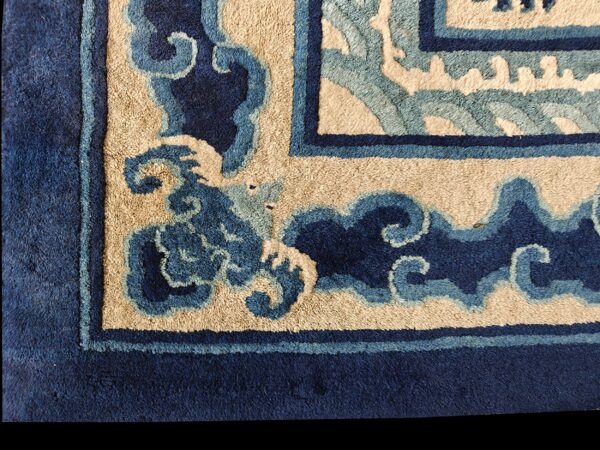 Detail shot of a high-pile rug corner with navy, light blue, and beige scrolling patterns.
