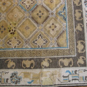 Gold, brown, and blue patterned rug showing a diamond field and repeating animal border designs.