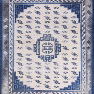 High-contrast blue and cream rug with a geometric border framing Ruyi cloud patterns and a Shou medallion.