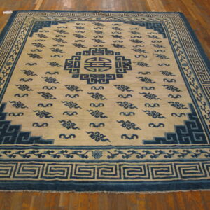 Large blue and cream rug featuring a central medallion and repeated cloud motifs on hardwood flooring.