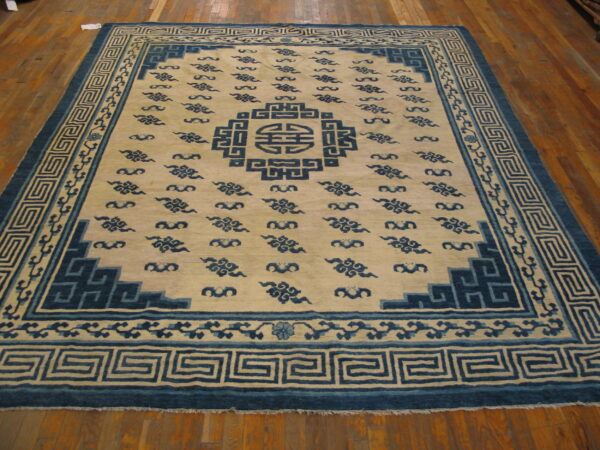 Large blue and cream rug featuring a central medallion and repeated cloud motifs on hardwood flooring.