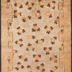 Beige area rug with scattered orange and brown medallions and a wide scrolling border.