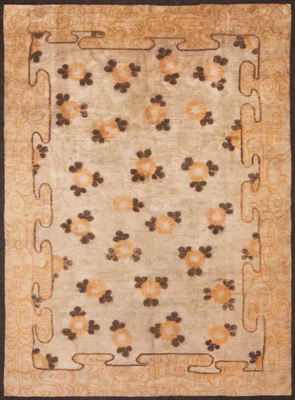 Beige area rug with scattered orange and brown medallions and a wide scrolling border.