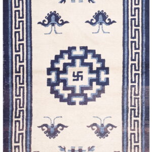 Off-white rug with navy and light blue geometric patterns, including a meander border and central symbol.