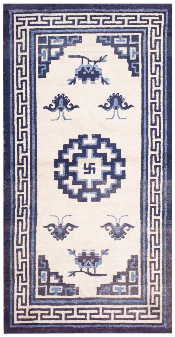 Off-white rug with navy and light blue geometric patterns, including a meander border and central symbol.