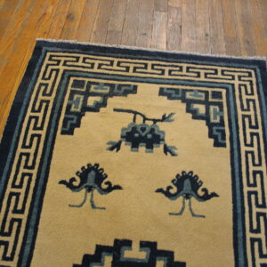 Cream rug featuring dark and light blue traditional geometric borders and abstract motifs on wood planks.