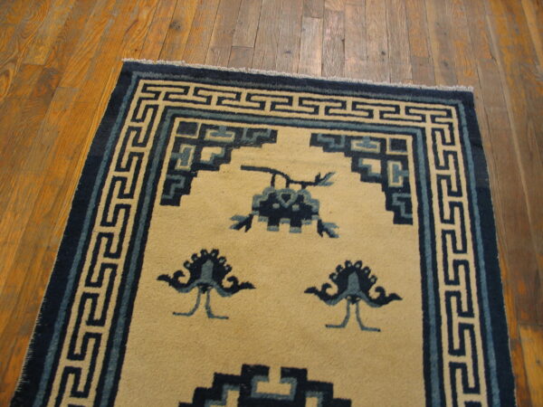 Cream rug featuring dark and light blue traditional geometric borders and abstract motifs on wood planks.