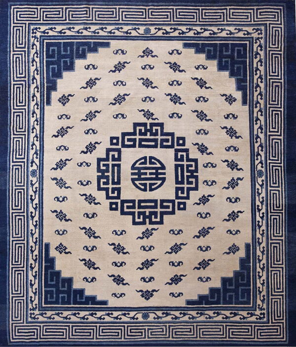 Beige rug featuring a dark blue geometric key border, stepped corners, and central medallion design.