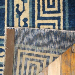 Detail shot of a blue and tan geometric rug, showing the medium pile surface and woven reverse structure.