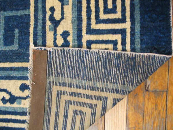 Detail shot of a blue and tan geometric rug, showing the medium pile surface and woven reverse structure.