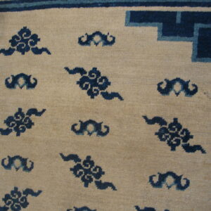 Low-pile beige rug with dark blue cloud motifs and a blue and light blue geometric corner border.